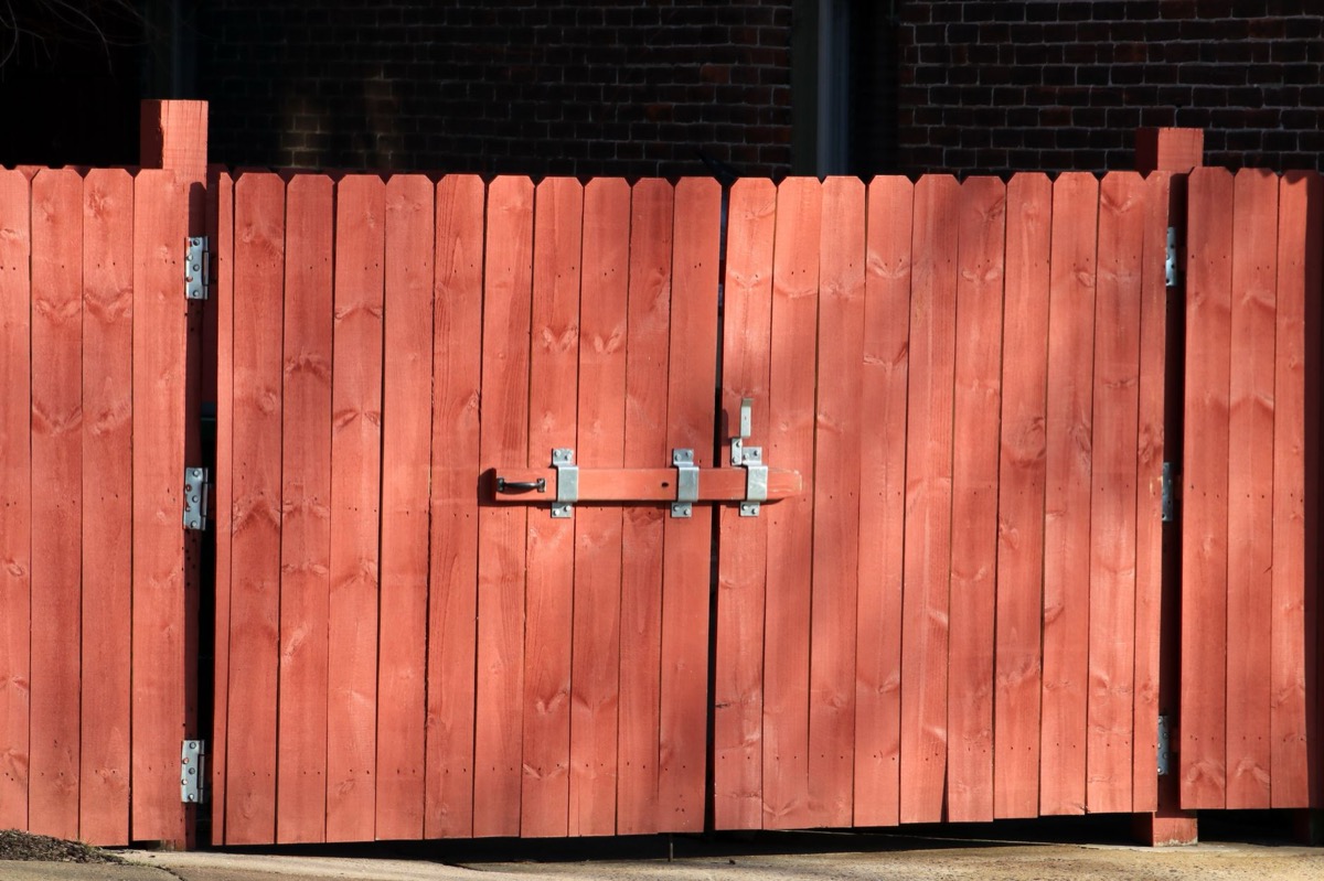 Partially installed wood privacy fence with posts set in concrete along a residential backyard perimeter